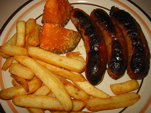 Chicken sausages, oven-baked chips and oven-baked pumpkin sprinkled with sesame seeds