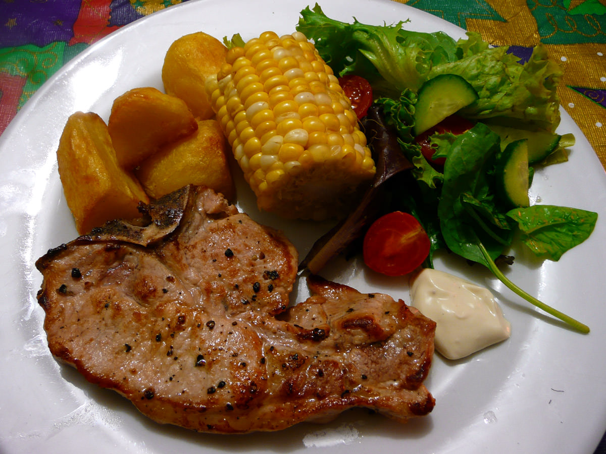 Pork chop, baked potatoes, corn, salad and aioli