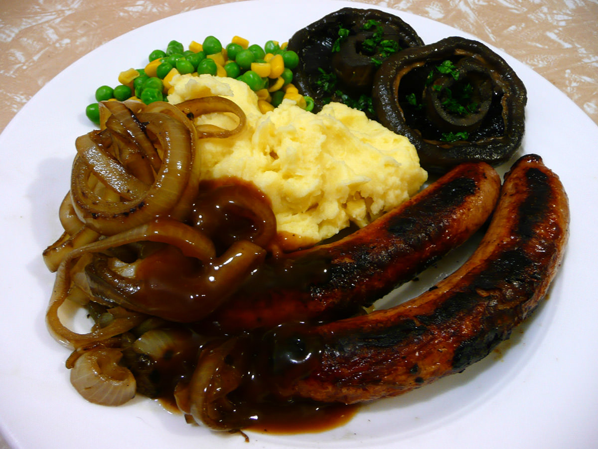 Bangers and mash, fried onions, peas and corn and mushrooms