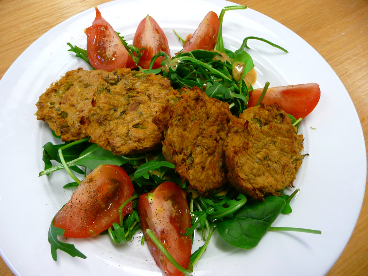 Ovenbaked salmon sweet potato and potato patties on rocket and spinach salad with tomato