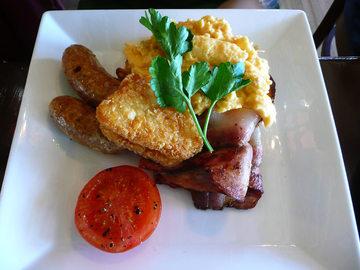 Traditional breakfast - sausages, bacon, tomato, ciabatta toast, hash browns and eggs - scrambled