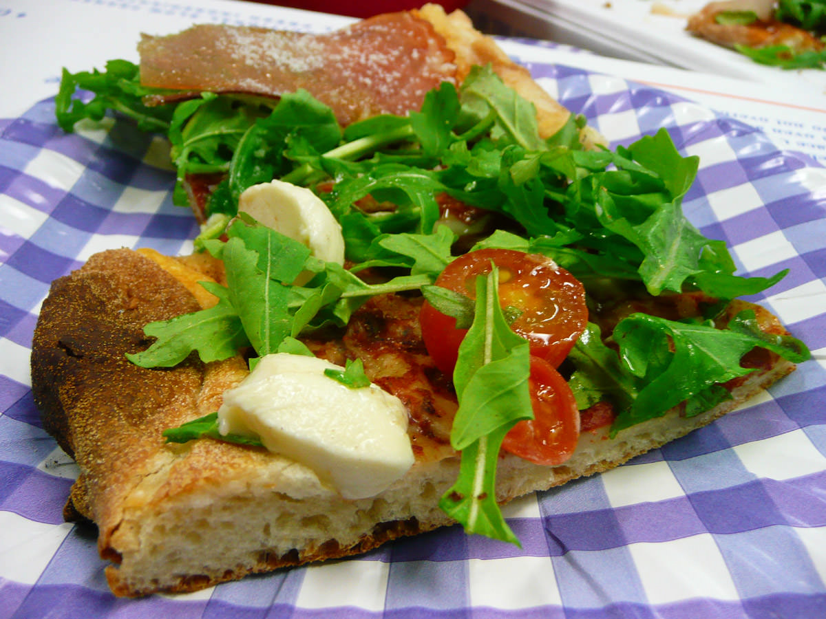 Slice of pizza with rocket, cherry tomatoes and bocconcini