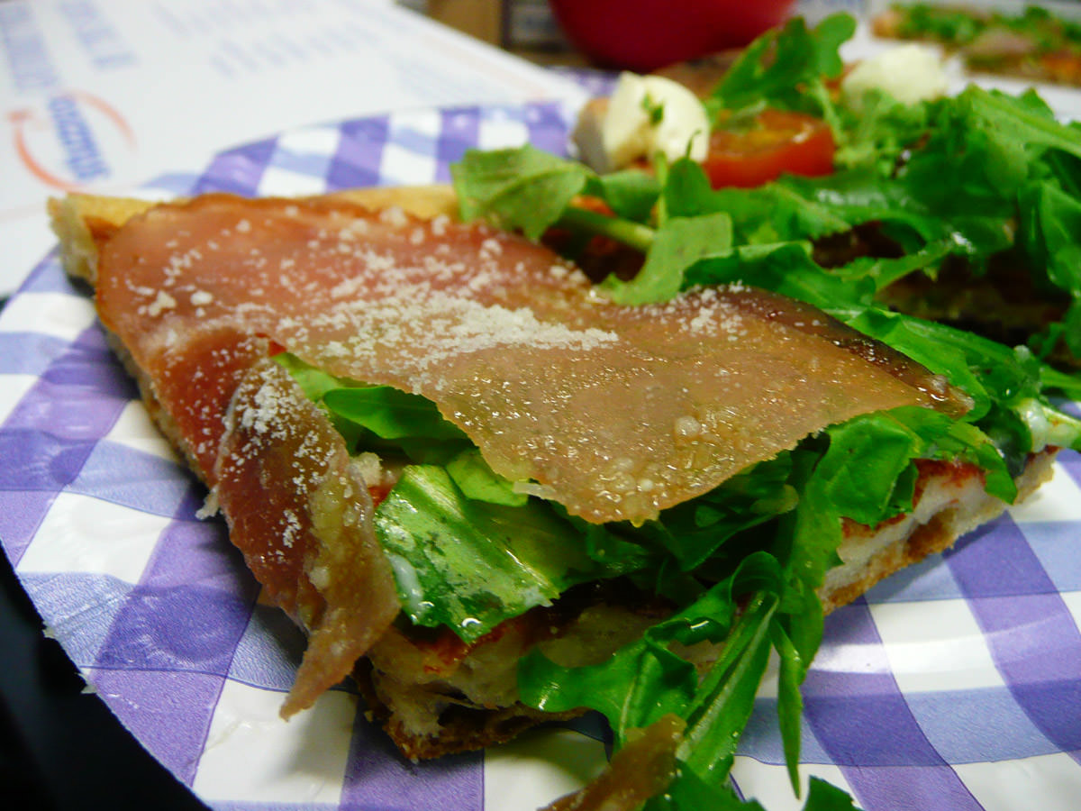 Slice of pizza with prosciutto and rocket
