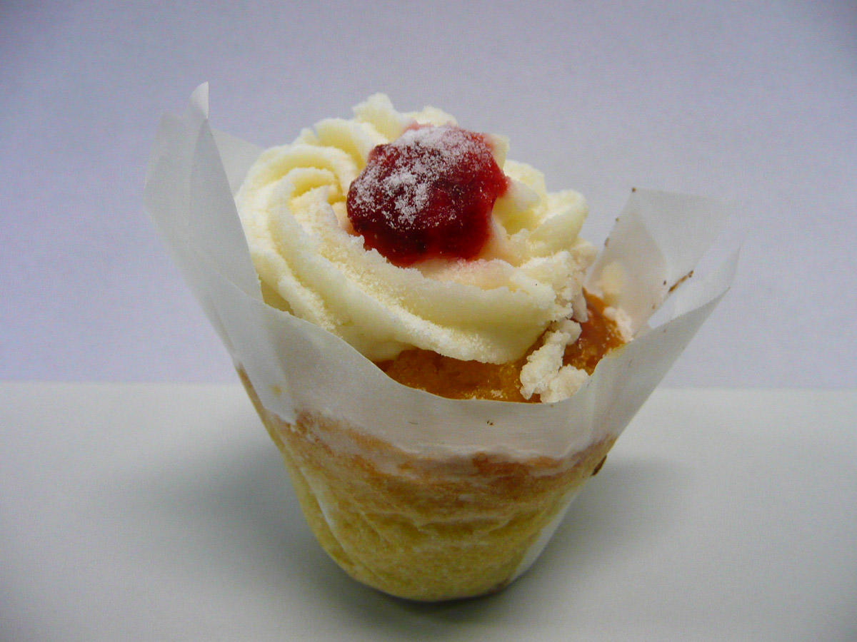 Little cake topped with icing, sugar and strawberry jam
