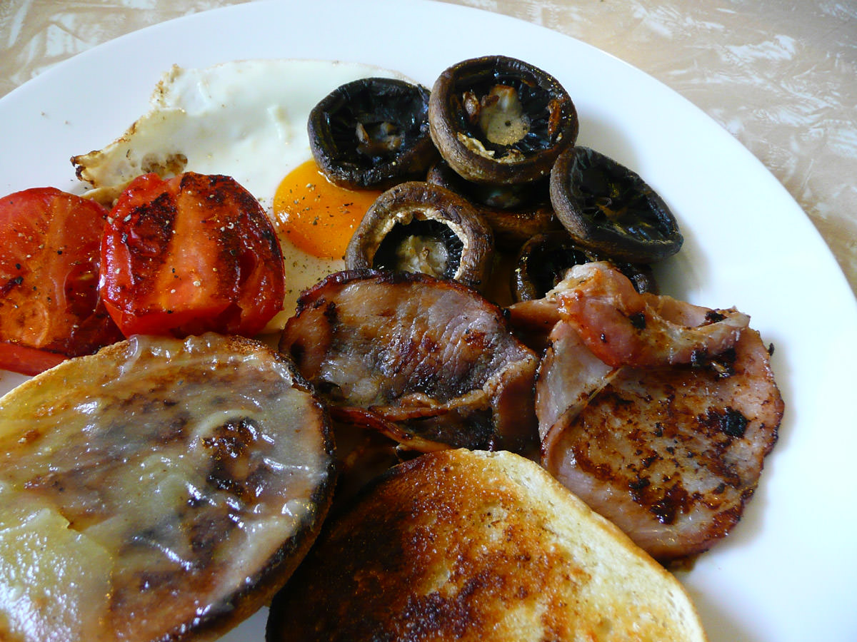 Fry-up - bacon, egg, tomato, mushrooms, English muffin close-up
