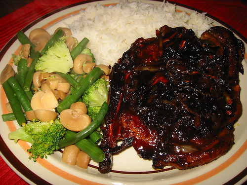 Plate shot of asian pork chop, rice and steamed vegies