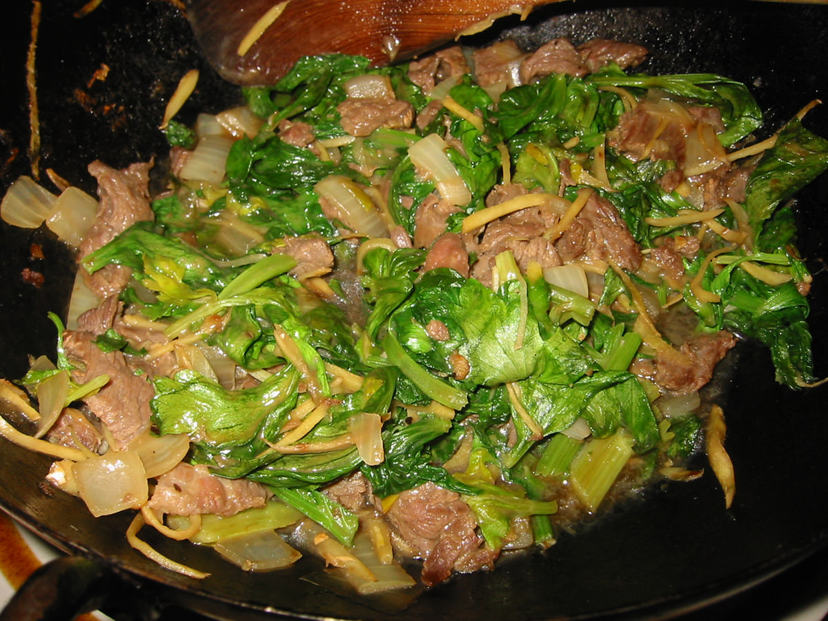 Stir-fried celery leaves with onion, ginger and beef in the wok