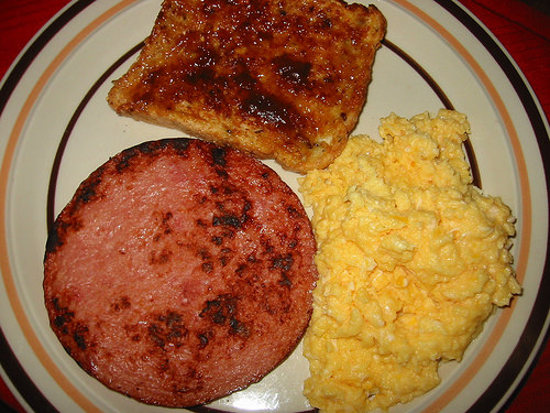 Fried ham steak, scrambled eggs and toast with strawberry spread