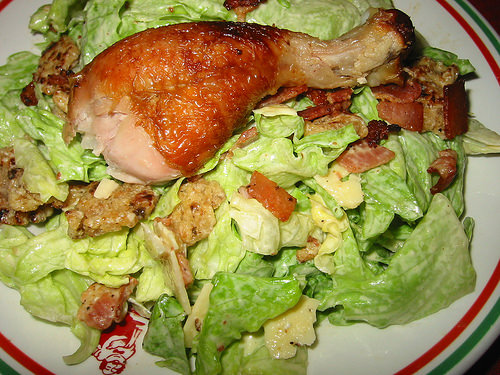 Caesar salad with a BBQ chicken drumstick