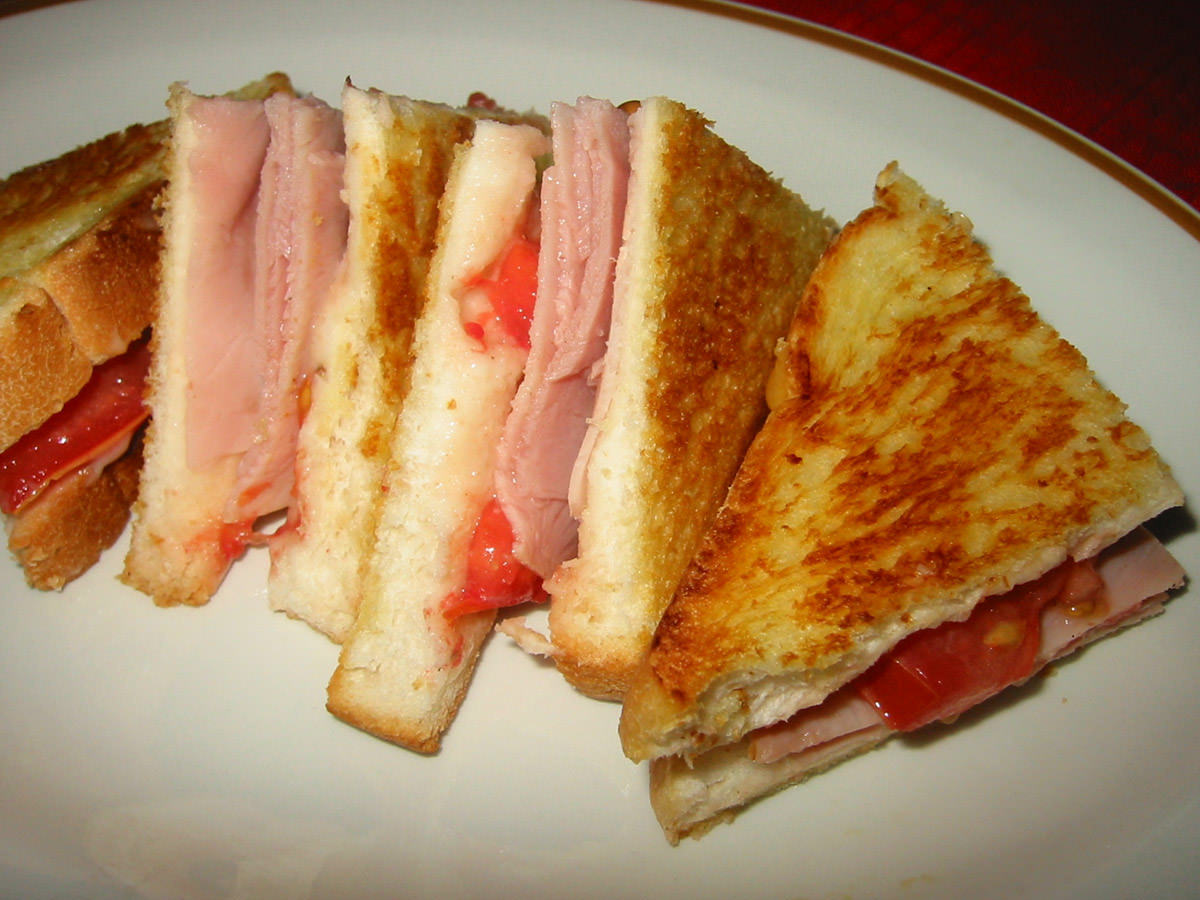 Toasted ham, tomato and mayo sandwich, cut into small triangles