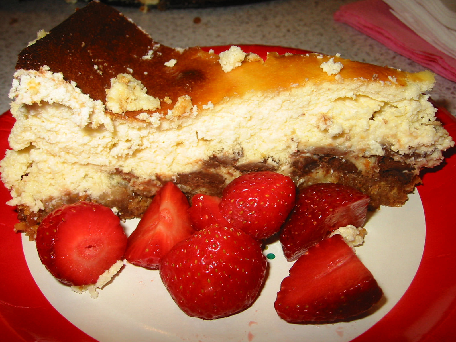 A slice of baked chocolate cheese cake with strawberries