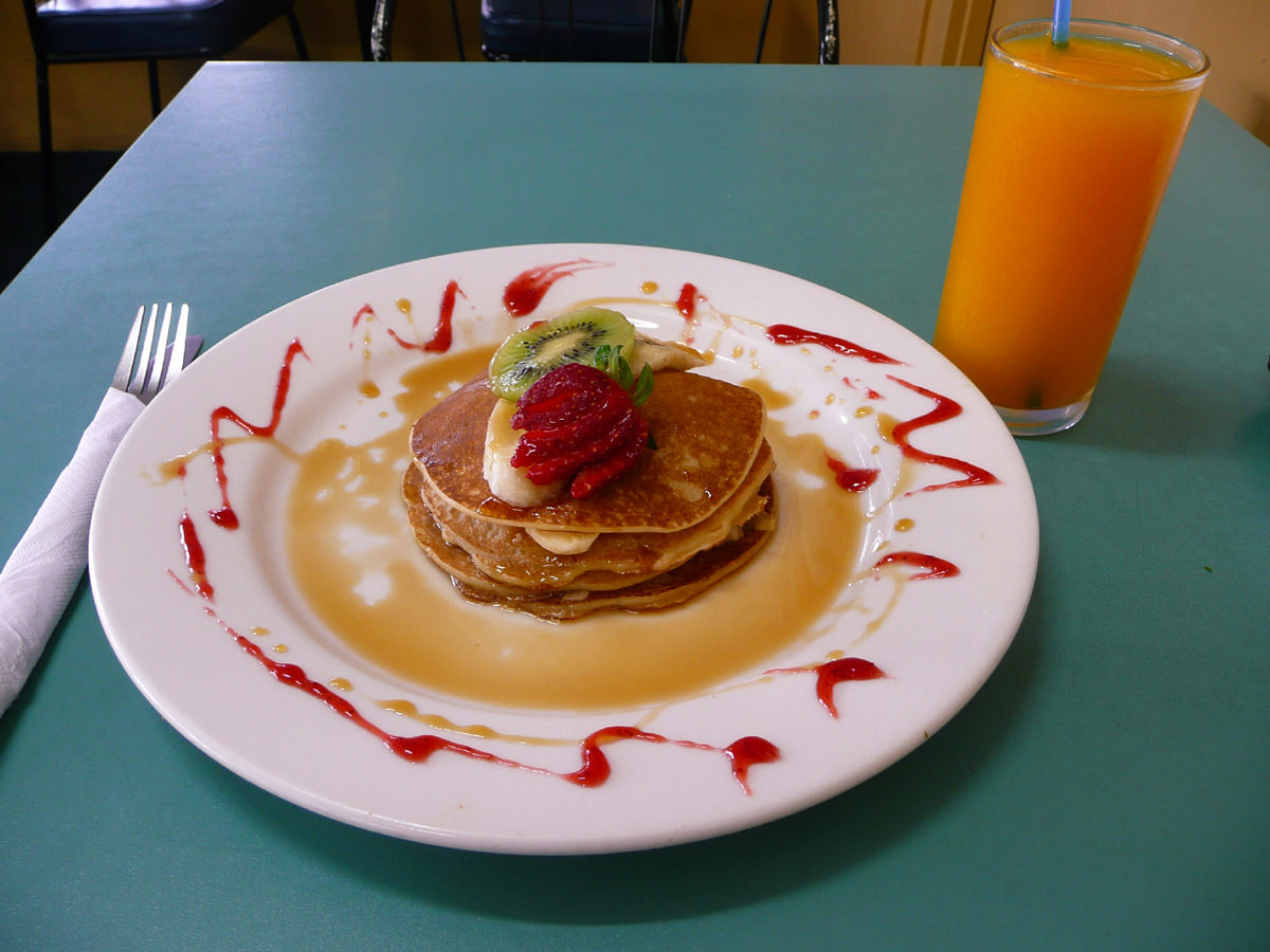 Pancakes with banana and maple syrup and a glass of freshly squeezed OJ