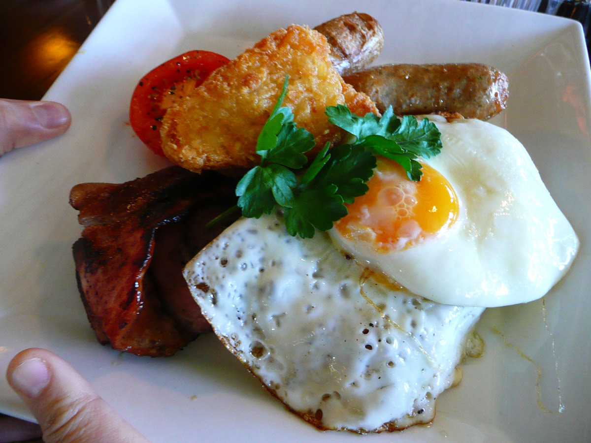 Traditional breakfast - sausages, bacon, tomato, ciabatta toast, hash browns and eggs - fried