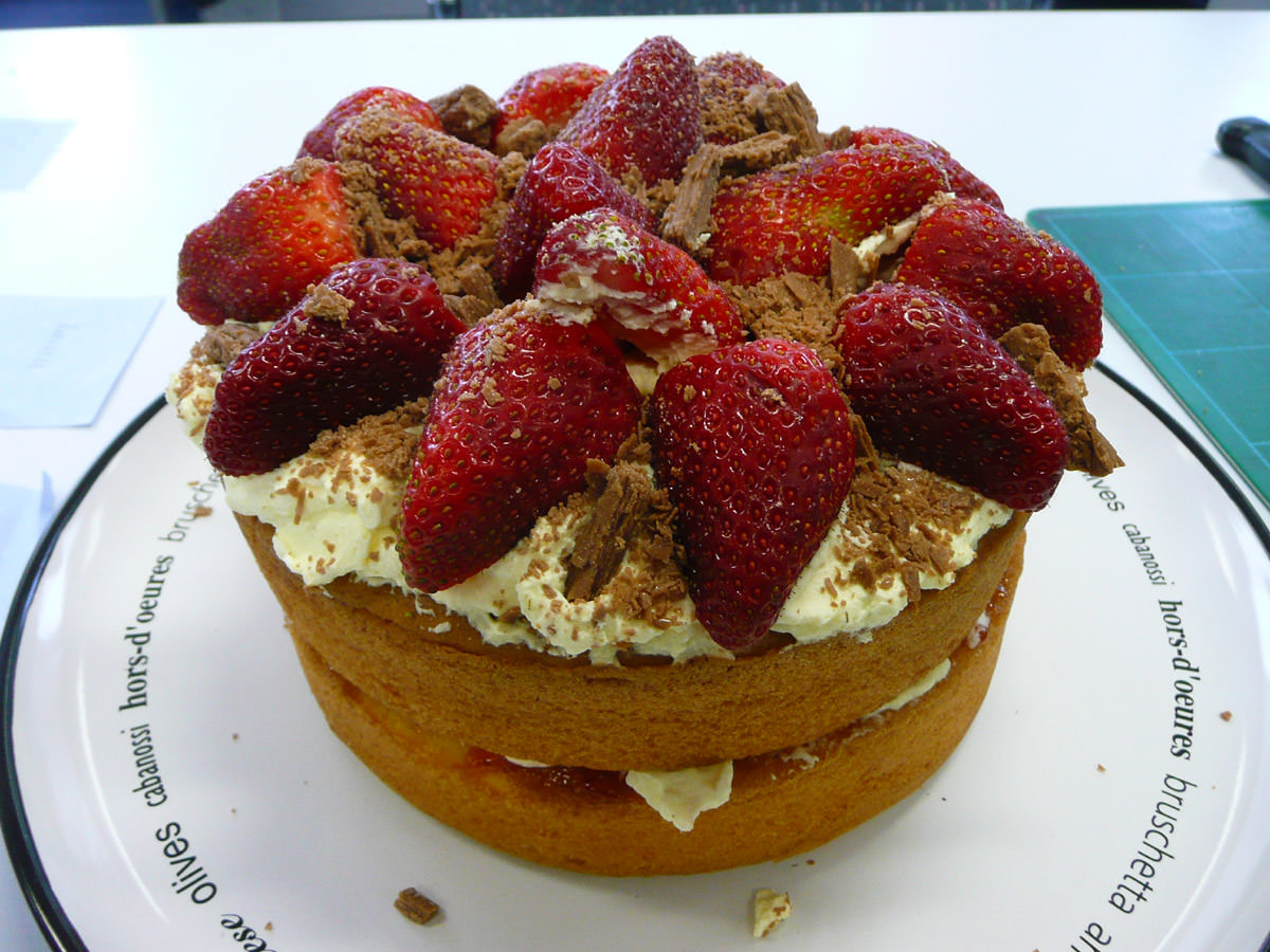 Two layers of sponge cake with cream, jam and strawberries