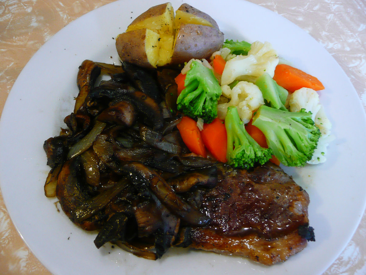 Porterhouse steak with onions and mushrooms, steamed vegetables and baked potato