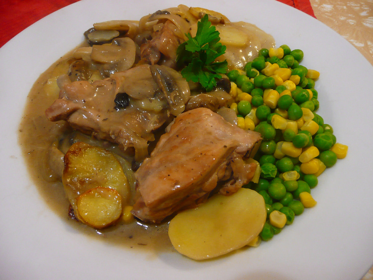 Baked chicken and mushroom casserole topped with sliced potatoes, served with corn kernels and peas