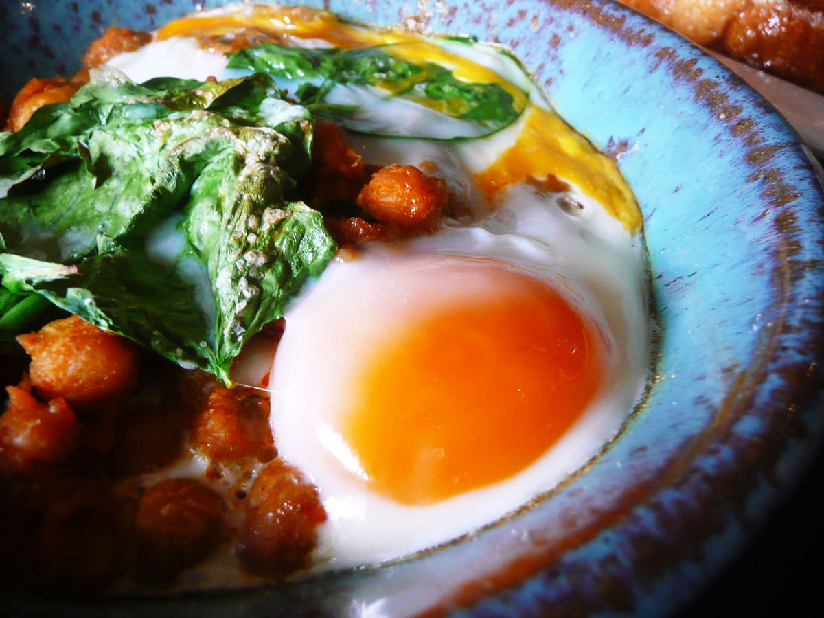 Baked eggs with spiced chickpeas and spinach - close-up of egg