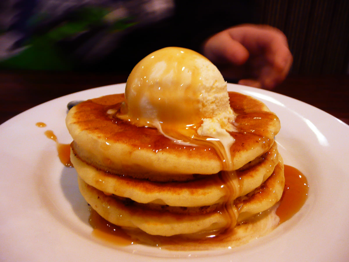Mini pancake stack with a scoop of vanilla ice cream and maple syrup