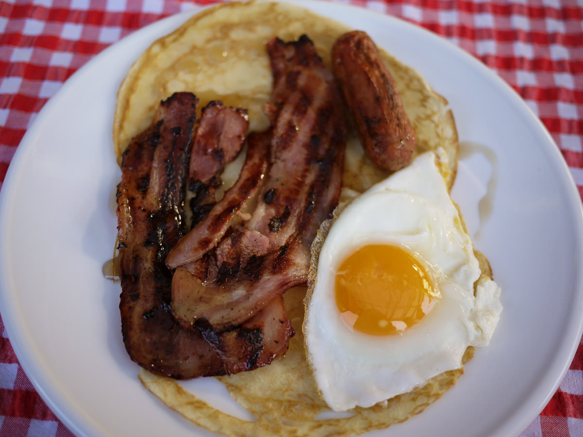 Pancakes with bacon, sausage, egg and maple syrup