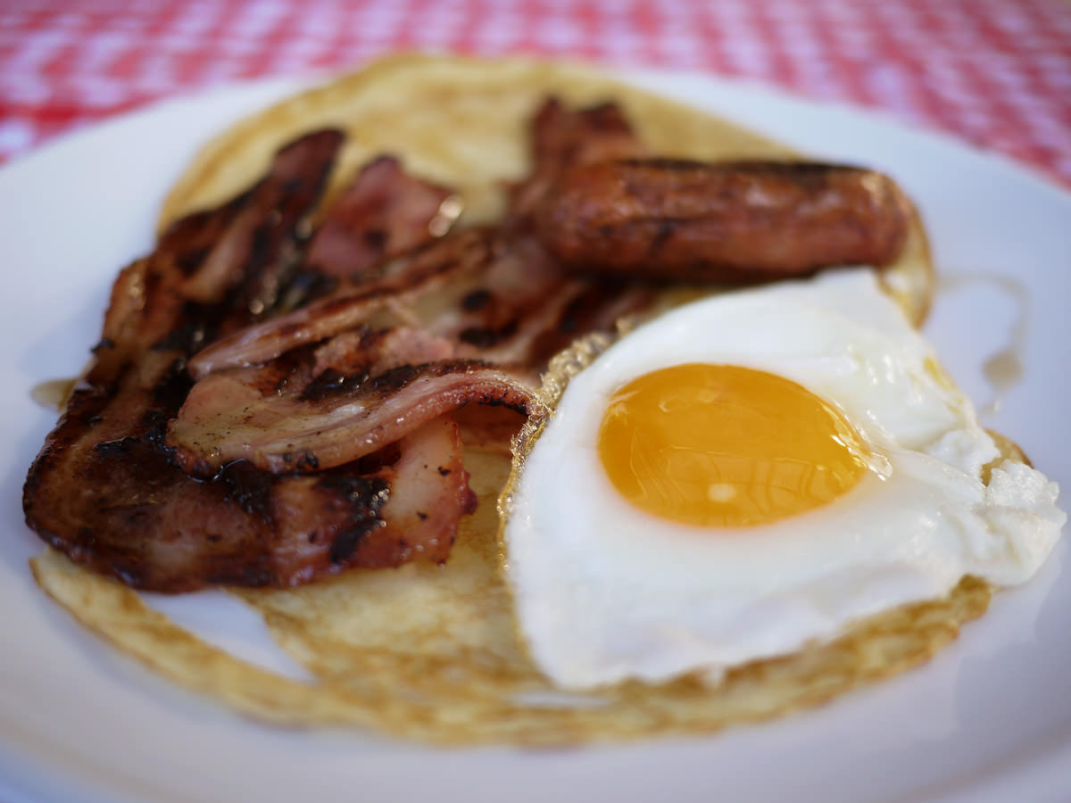 Pancakes with bacon, sausage, egg and maple syrup