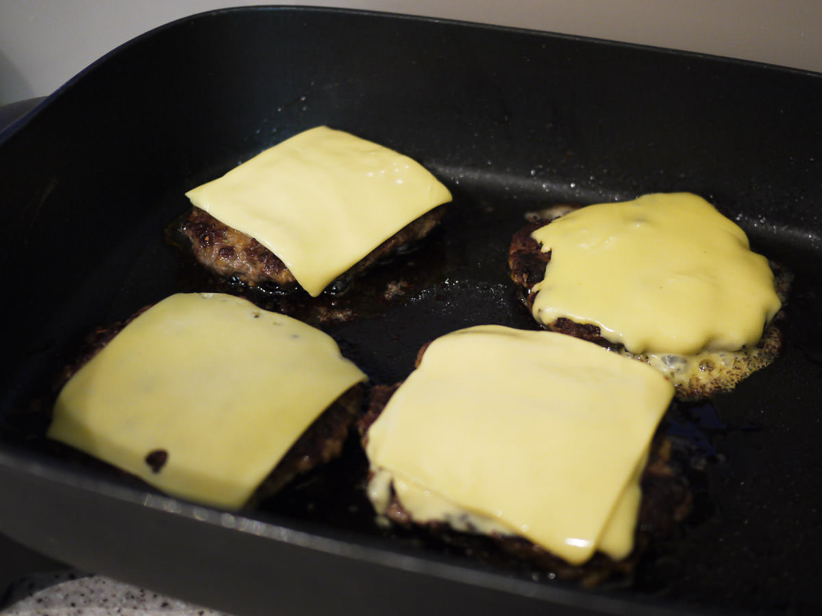 Cheese burgers sizzling in the pan