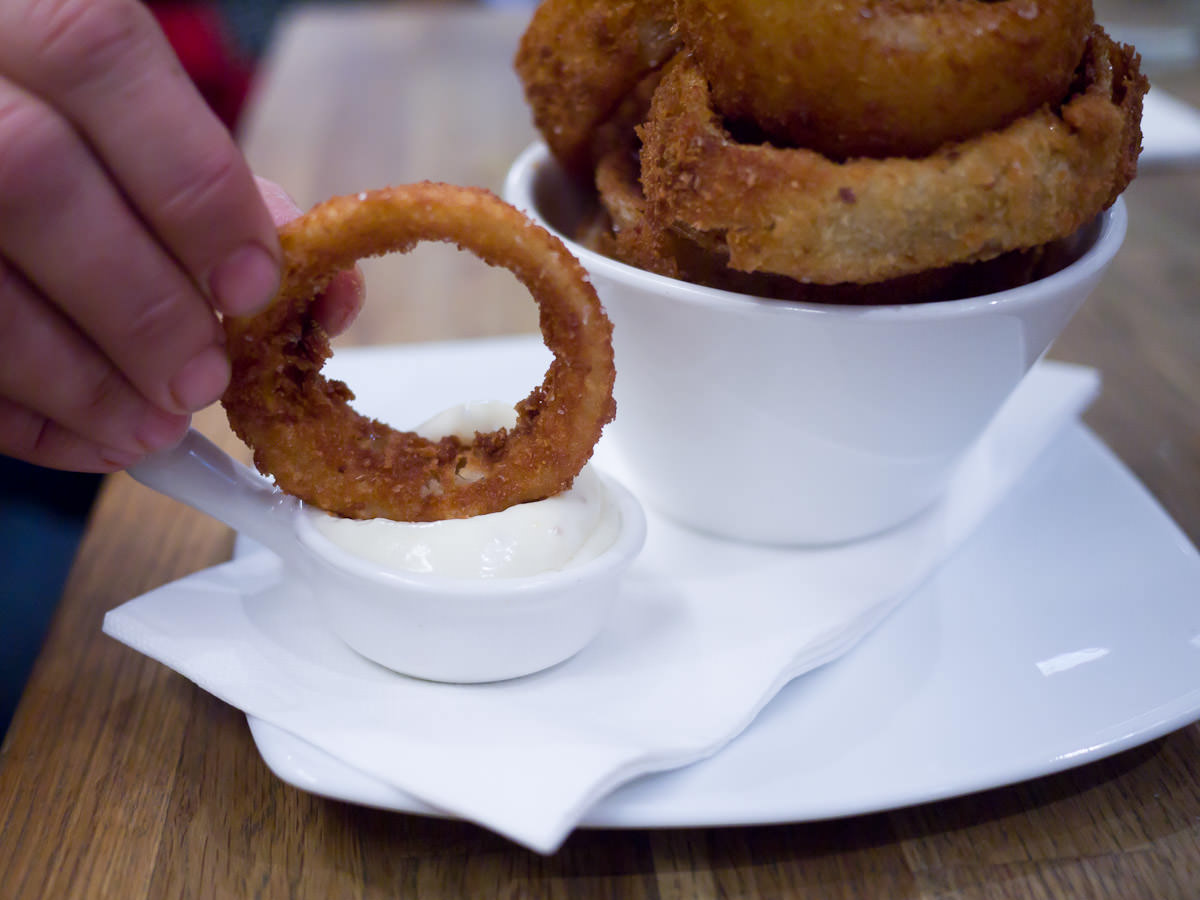 Dipping onion ring into aioli