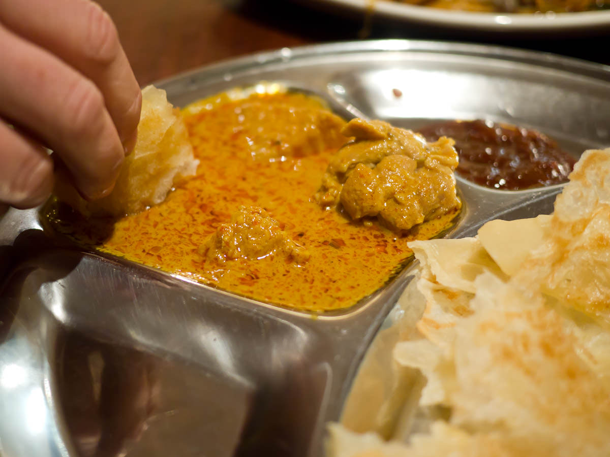 Dipping roti canai into curry chicken