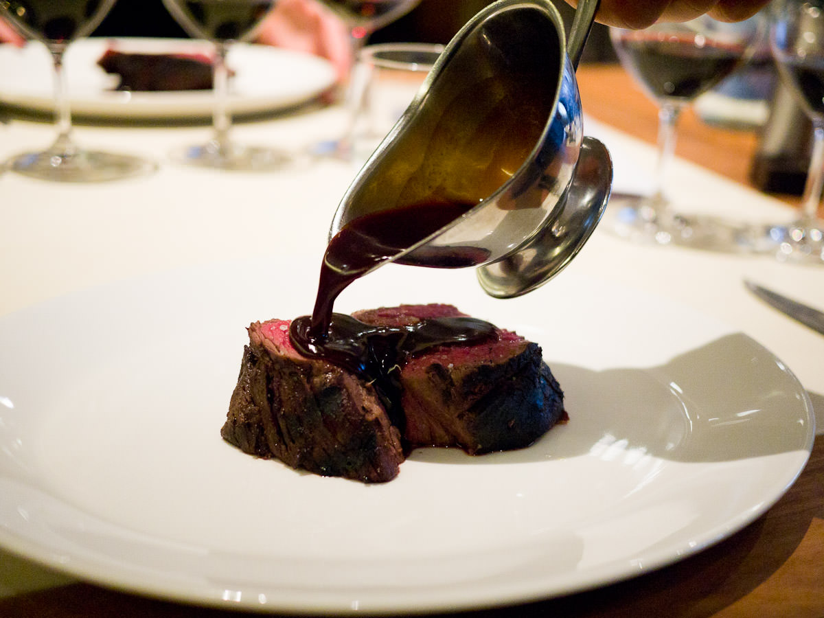 Red wine sauce being poured over slow cooked charred Rangers Valley beef fillet