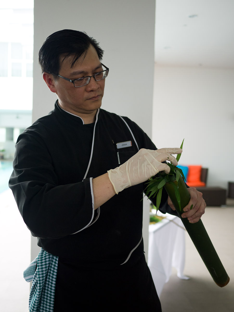 Stuffing young tapioca leaves into the bamboo tube that's been filled with the chicken mixture