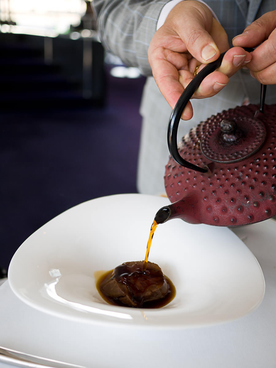 Pouring the oxtail consomme over the pure-bred wagyu, bitter chocolate black pudding