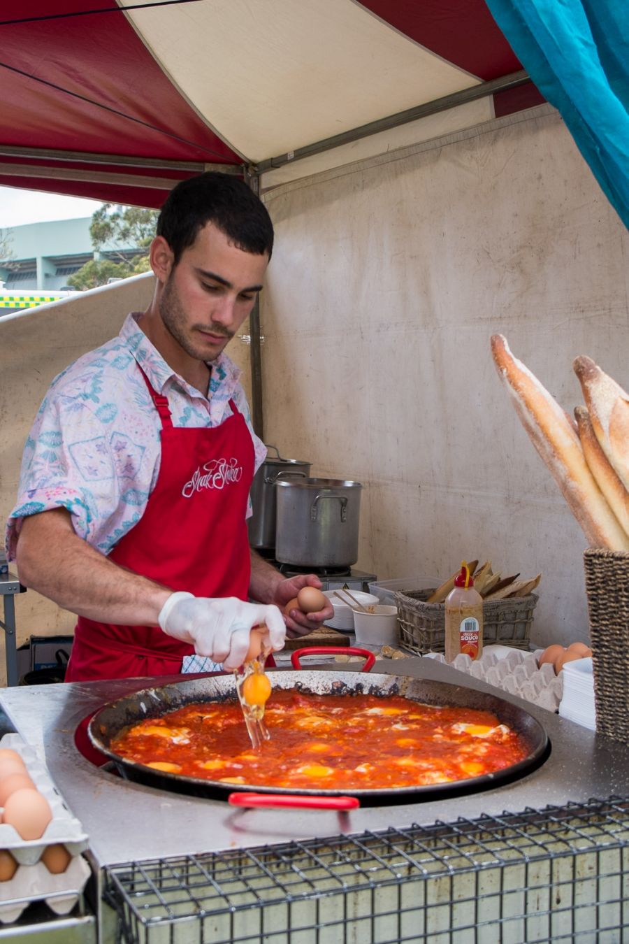 Cracking eggs into the spicy tomato sauce at the Shak Shuka stall
