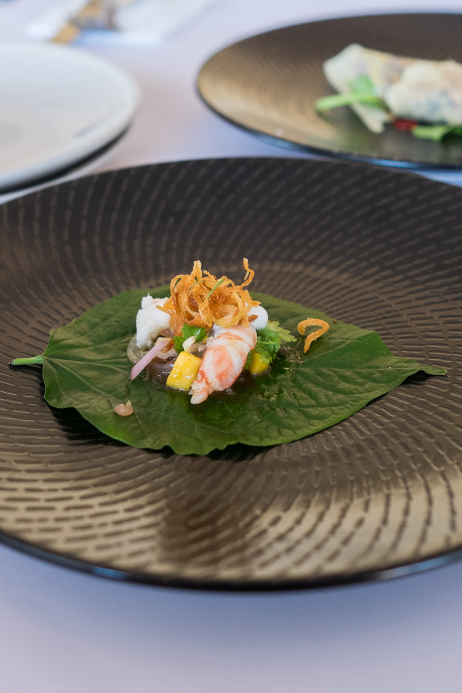 Miang of prawn with mango, herbs, coconut milk and lime, served on betel leaf